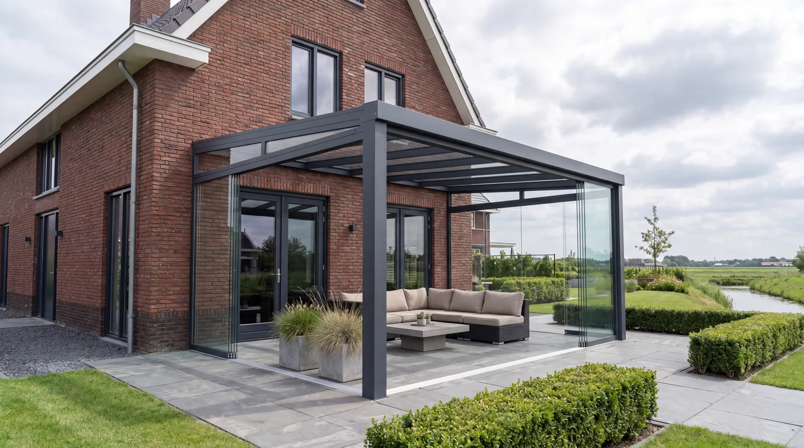 Verandera Elegance veranda met glazen schuifwanden bij baksteen woning aan het water — moderne aluminium tuinkamer