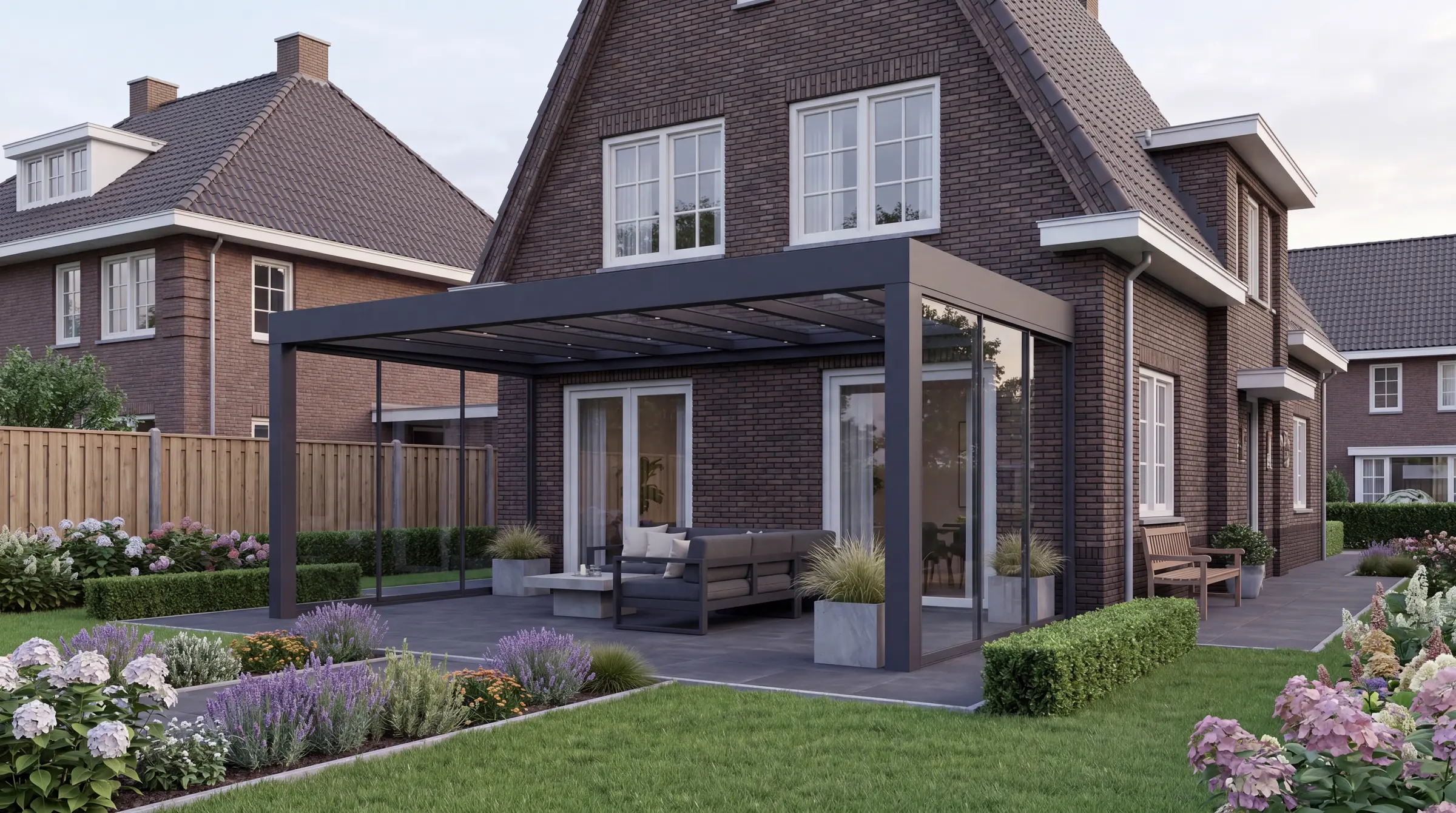 Verandera Prestige veranda in antraciet bij klassieke bakstenen woning met dakkapel en bloementuin — robuuste aluminium veranda met massieve staanders